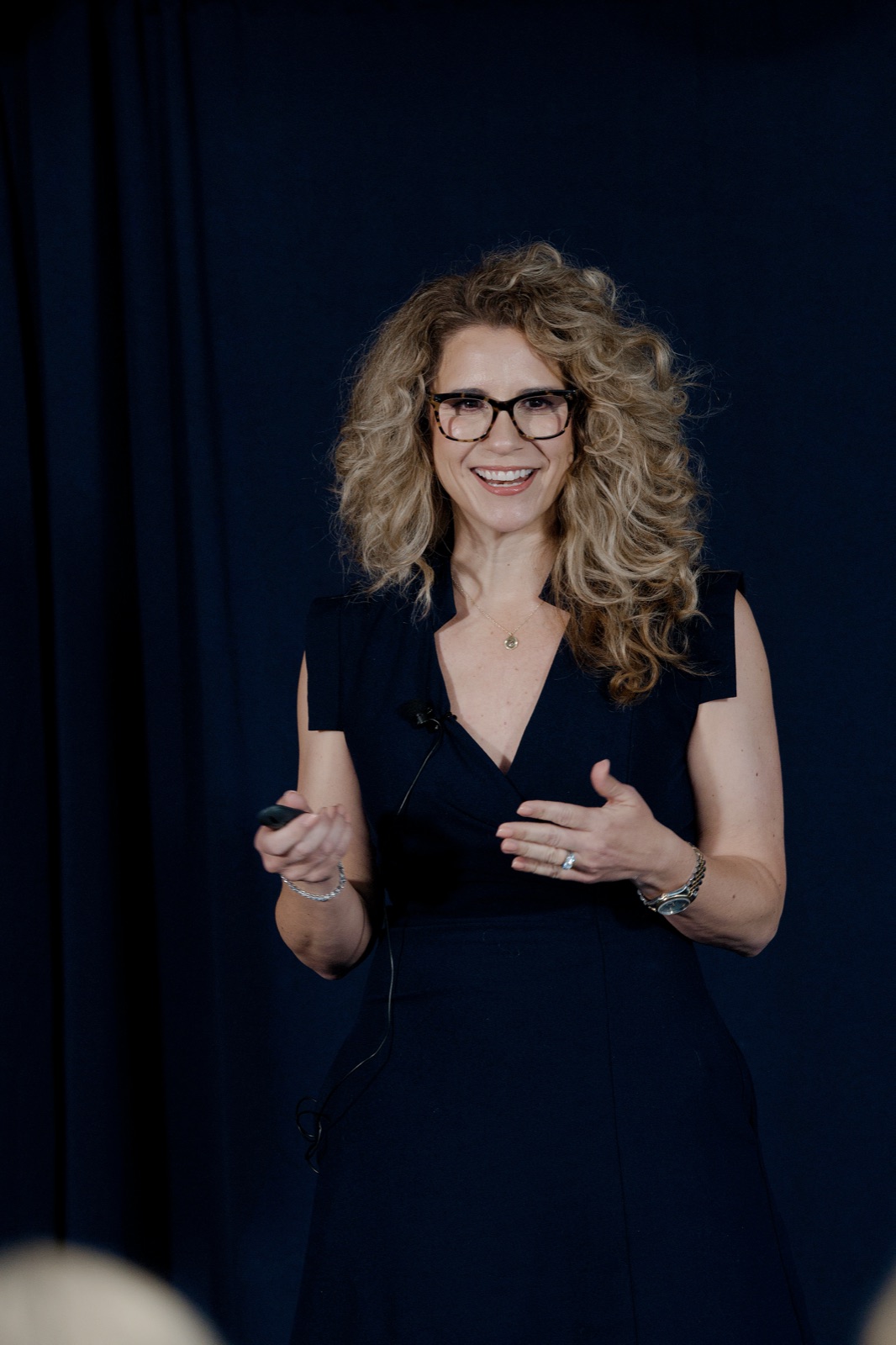 A FirstHome IQ speaker mid-sentence on stage, clicker in hand