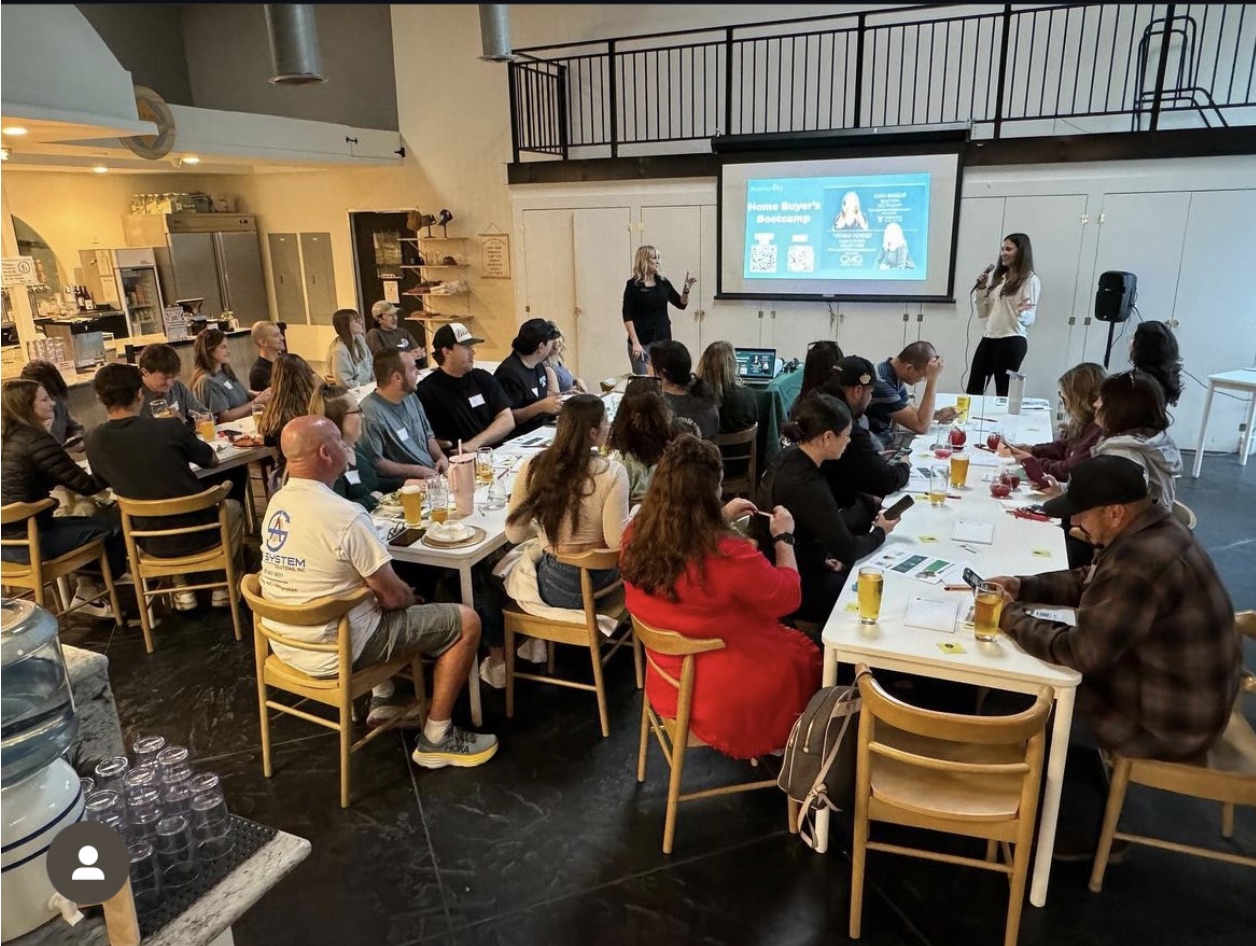 A packed Home Buyer's Bootcamp, presenters at the screen and every table full